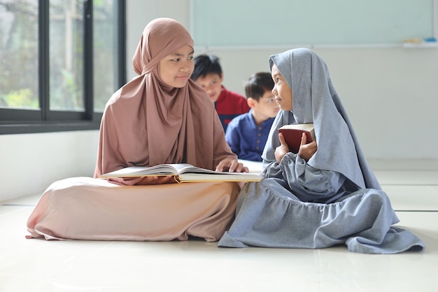 Asian Muslim girls in hijab learning about Islam religion Group of children reads the holy book Qur