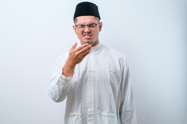 Asian muslim man having bad breath problem during fasting in ramadan moth over white background