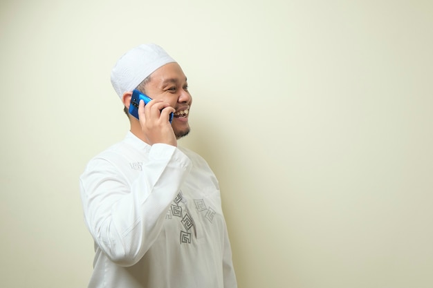 Asian Muslim man looks happy when receiving a call from his brother. The man celebrated Eid Mubarak with confident gesture