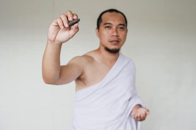 Asian muslim man performing the Jamarat ritual (stoning the devil) during Hajj season