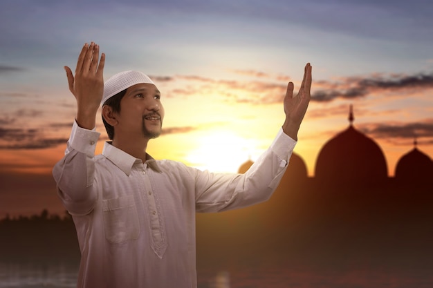 Asian Muslim man standing while raised hands and praying