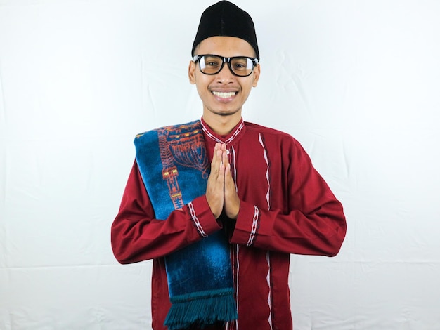 Asian Muslim man wearing glasses smiling to give greeting during Ramadan and Eid Al Fitr celebration