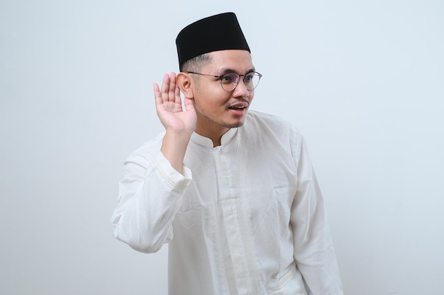 Asian muslim man wearing a typical arab clothes trying to listening a gossip isolated on white background