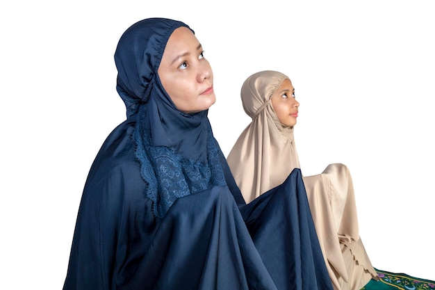 Asian Muslim mother and daughter in a hijab raised hands and praying