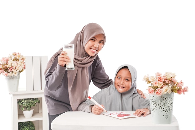 Asian muslim mother is serving her son a glass of milk while studying