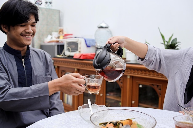 Asian muslim people pouring water, having dinner together at home. Break fasting concept.