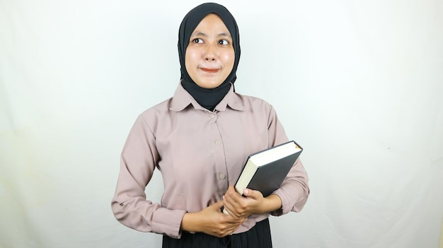 Asian Muslim student holding book looking at camera Back to school college concept