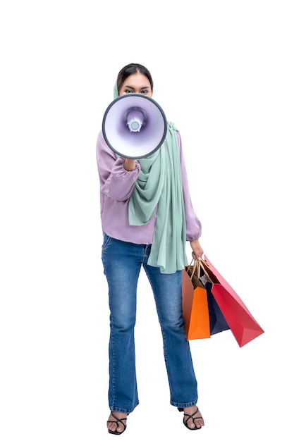 Asian Muslim woman in a headscarf holding a megaphone and shopping bags