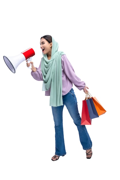 Asian Muslim woman in a headscarf holding a megaphone and shopping bags