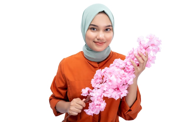 Asian Muslim woman in a headscarf holding a pink flower