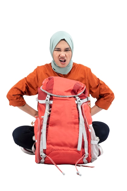 Asian Muslim woman in a headscarf sitting with a backpack with an upset expression