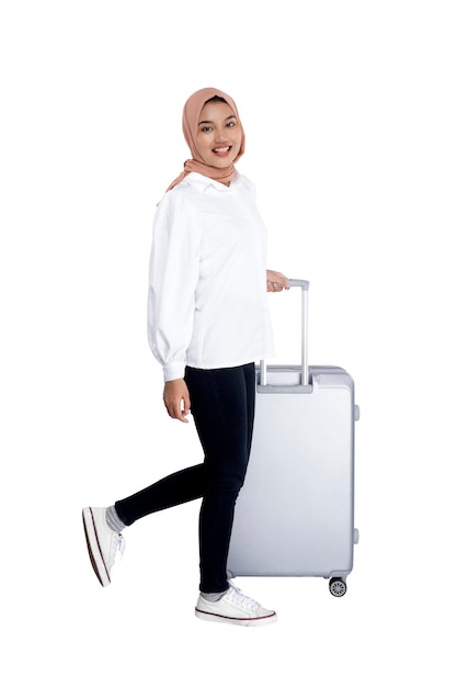 Asian Muslim woman in a headscarf walking with a suitcase