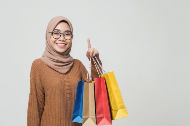 Asian Muslim woman smiles points to shopping bags on white background