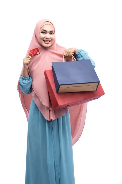 Asian Muslim woman in veil holding credit card and shopping bags