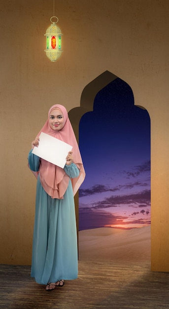 Asian Muslim woman in veil holding empty paper