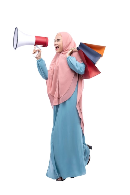 Asian Muslim woman in veil holding megaphone and shopping bags