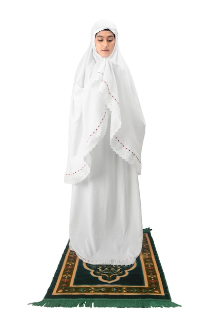 Asian Muslim woman in a veil standing while raised hands and praying isolated over white background