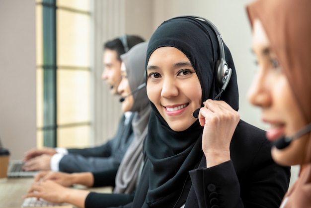 Asian muslim woman wearing microphone headsets working with team in call center 