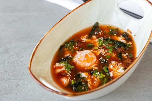 Asian noodle soup in bowl on gray surface