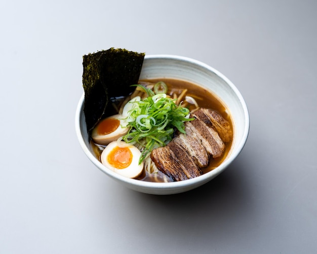 Asian noodle soup ramen with meat tofu vegetables nori and egg in white bowl japanese delicious cuis