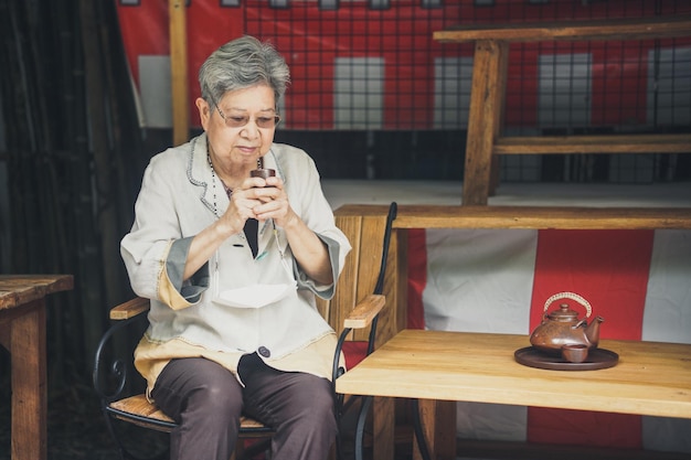 Asian old elderly female elder woman drinking tea in garden senior leisure lifestyle