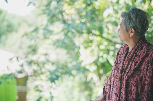 Asian old elderly female elder woman resting relaxing in garden. senior leisure lifestyle