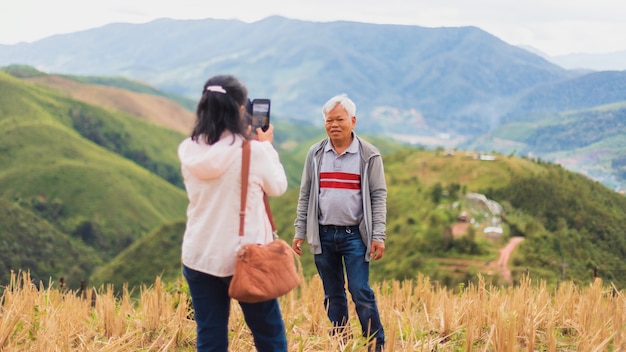 Asian old senior couples use smartphone to selfie at the top of mountain