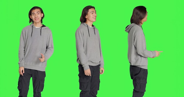 Asian person shows approval sign over greenscreen backdrop doing yes gesture and smiling Young man with optimistic facial expressions feeling pleased and expressing agreement