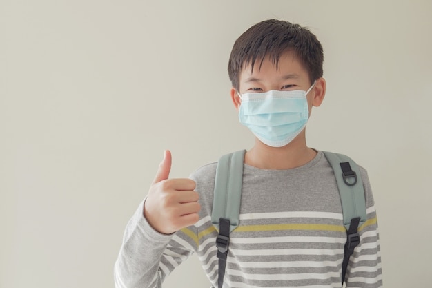 Asian preteen wearing mask and giving thumb up