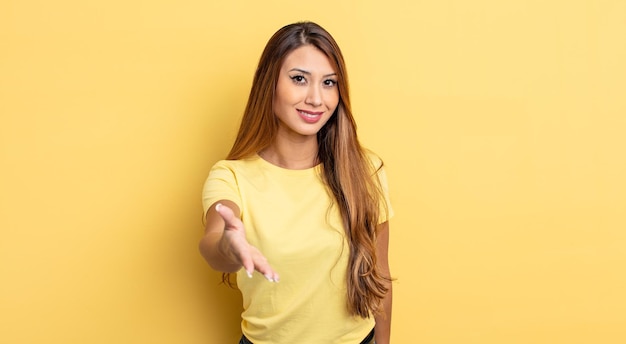 Asian pretty woman smiling, looking happy, confident and friendly, offering a handshake to close a deal, cooperating