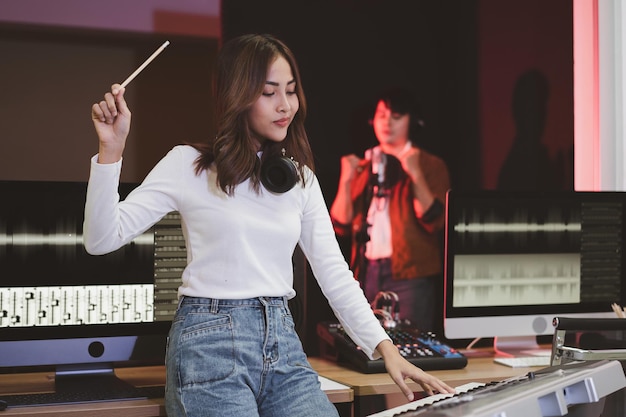 Asian producer woman in white shirt standing by the sound mixing console