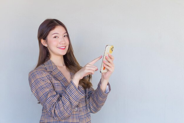 Asian professional woman with long hair wearing plaid suit while she acts enjoy with success of work