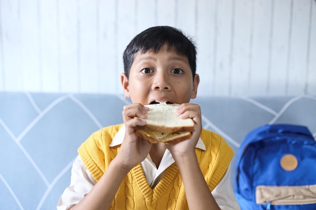 Asian schoolboy eating bread toast for breakfast before going to school in the morning