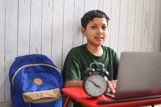 Asian schoolboy studying at home using a laptop and study online with video call teacher at home.