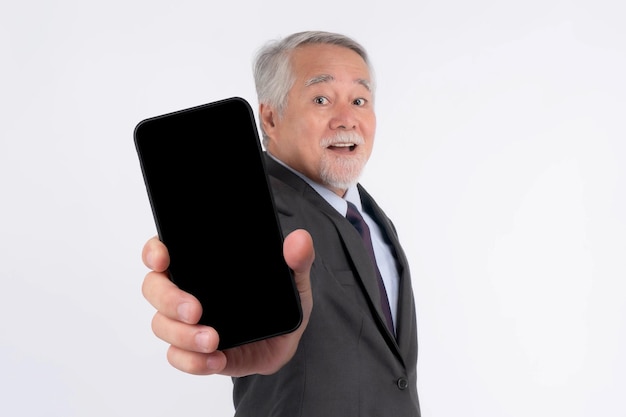 Asian senior businessman old man with suit feel happy pointing finger to big smart phone with blank screen black screen isolated on white background smart phone empty display Mock Up Image