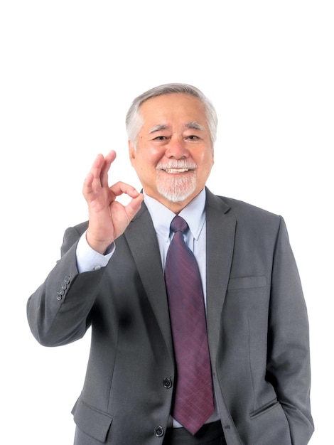 Asian senior businessman old man with suit and tie showing ok gesture hand standing and looking at camera isolated on white background with copy space lifestyle senior male concept