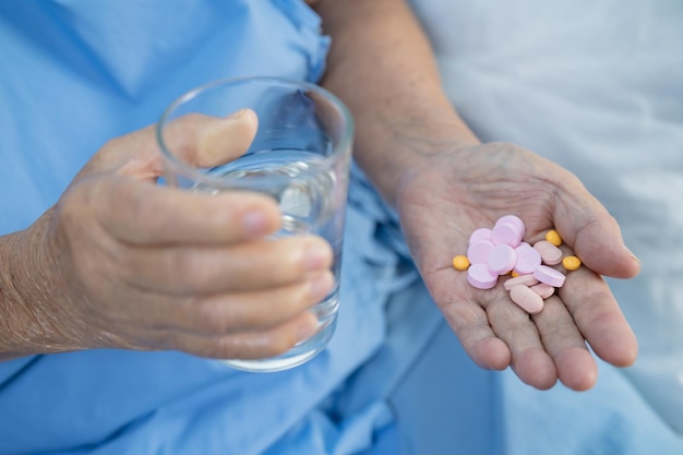 Asian senior elderly old lady woman holding Vitamin pills drug in her hand healthy strong medical concept