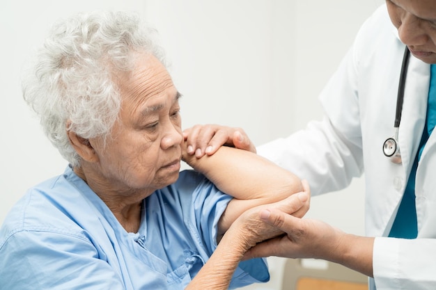 Asian senior or elderly old lady woman patient feel pain her elbow on bed in nursing hospital ward healthy strong medical concept