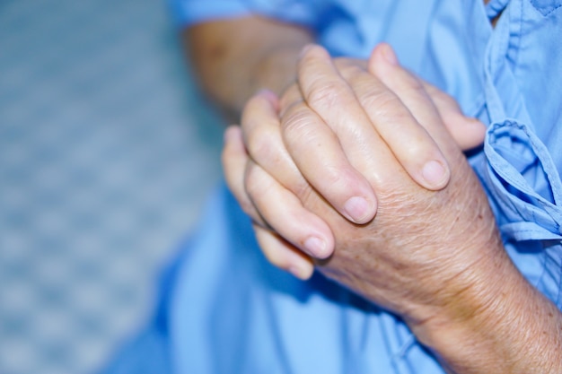 Asian senior or elderly old lady woman patient hold her hand with hope while sitting 