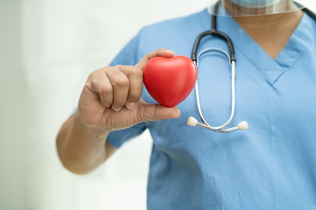 Asian senior or elderly old lady woman patient holding red heart in her hand on bed in nursing hospital ward, healthy strong medical concept