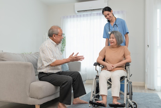 Asian senior man with woman caregiver talking encouraging to his wife patient sit on wheelchair