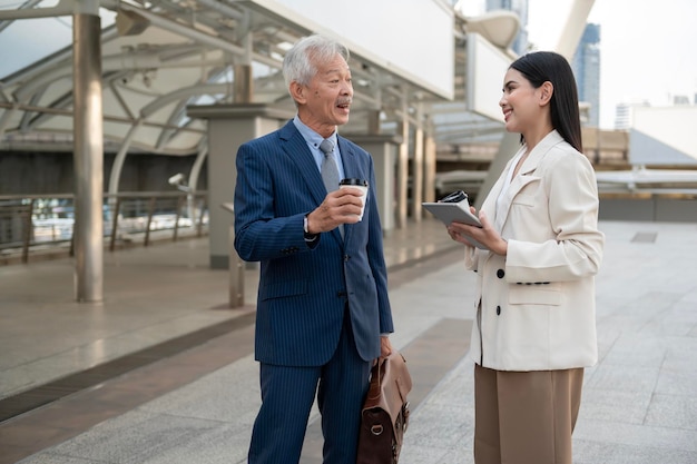 Asian senior mature middle aged businessman and young businesswoman having a discussion