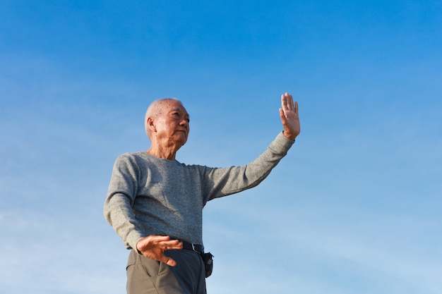 Asian Senior old man practice Taichi Chinese Kungfu on the beach