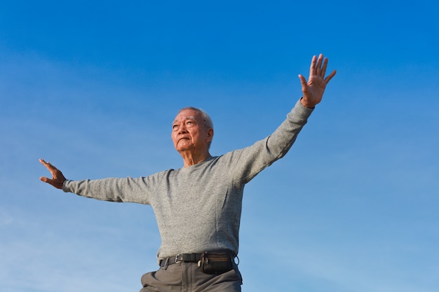 Asian Senior old man practice Taichi Chinese Kungfu on the beach