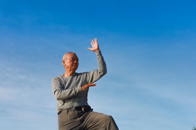 Asian Senior old man practice Taichi Chinese Kungfu on the beach