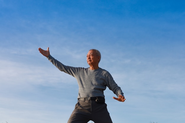 Asian Senior old man practice Taichi Chinese Kungfu on the beach