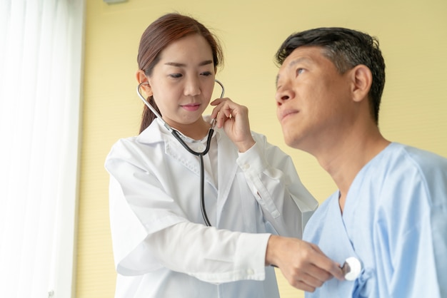 Asian senior patient on hospital bed discussing with female doctor