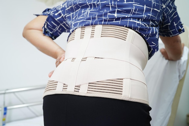 Asian senior wearing elastic support belt can help reduce back pain