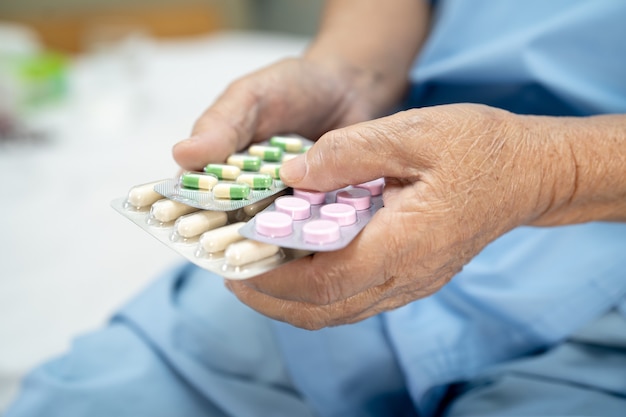 Asian senior woman patient holding antibiotics capsule pills in blister packaging