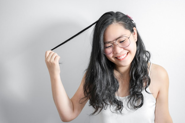 Asian Shy girl happy and smile with playing her hair in studio light white background